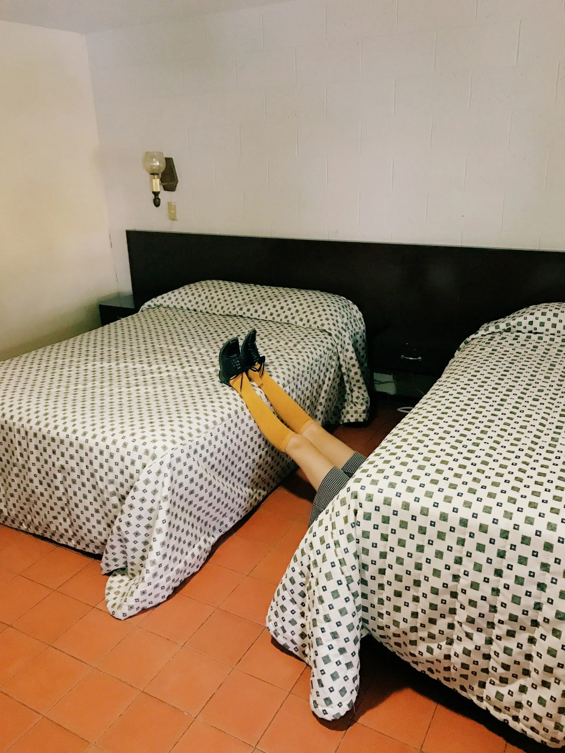 Guest looking underneath a hotel bed.